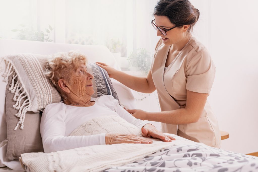 Elderly,Woman,In,Hospital,Bed,With,Social,Worker,Helping,Her